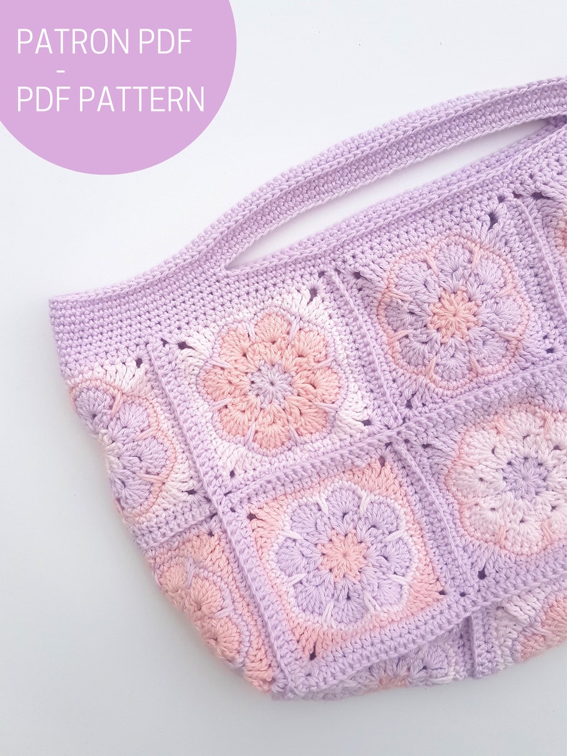 May include: A crocheted tote bag with a light purple and pink color gradient. The bag has a wide, flat handle and is made of square granny stitch motifs.