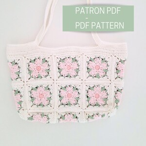 K&ouml;nnte beinhalten: Eine wei&szlig;e H&auml;kel-Tragetasche mit rosa und gr&uuml;nen Blumen. Die Tasche ist mit einem PDF-Muster zum Kauf erh&auml;ltlich. Der Text "PATRON PDF - PDF PATTERN" ist auf dem Bild zu sehen.