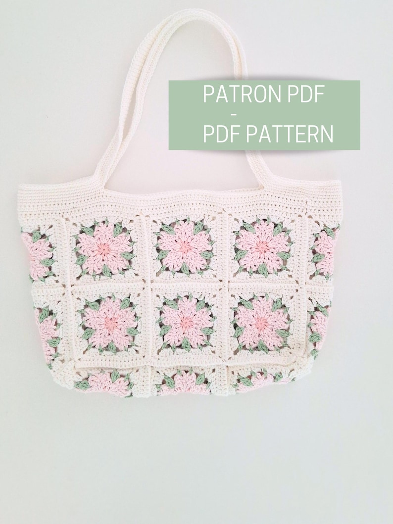 K&ouml;nnte beinhalten: Eine wei&szlig;e H&auml;kel-Tragetasche mit rosa und gr&uuml;nen Blumen. Die Tasche ist mit einem PDF-Muster zum Kauf erh&auml;ltlich. Der Text "PATRON PDF - PDF PATTERN" ist auf dem Bild zu sehen.