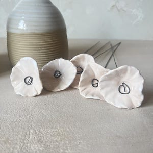 5 små, rundade vita keramikblommor på tråd
