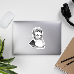 May include: Black and white line drawing of a man with a long beard and mustache. He is wearing a suit jacket and has a serious expression on his face.