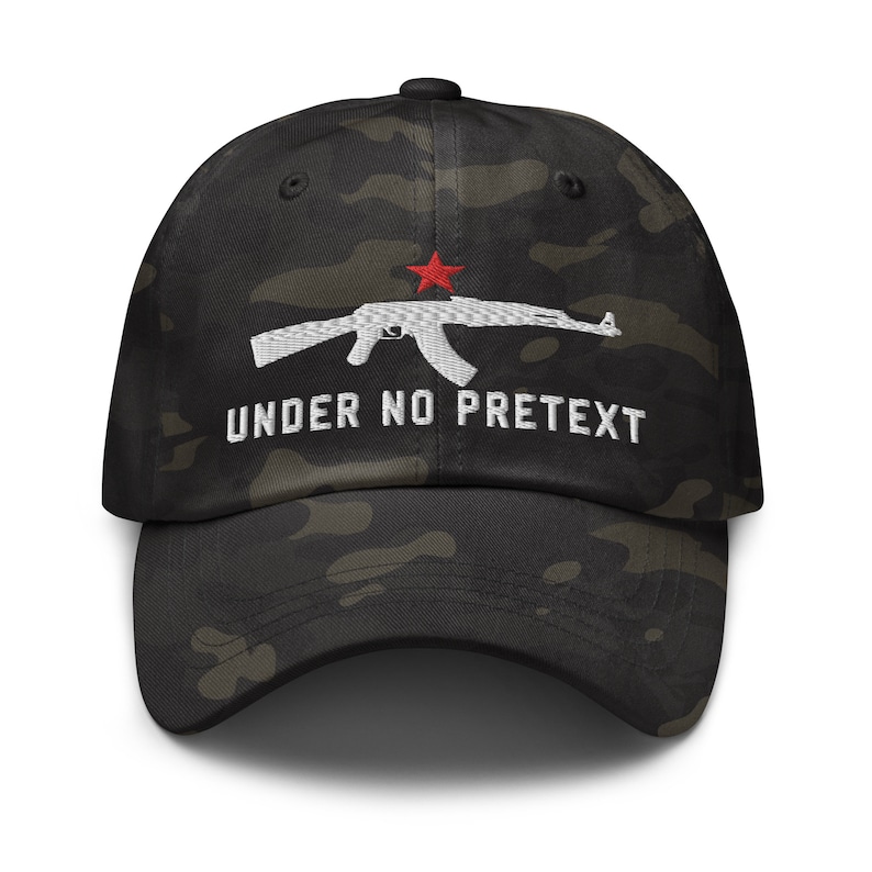 May include: A black and green camouflage baseball cap with a white embroidered image of an AK-47 rifle with a red star and the text "UNDER NO PRETEXT".