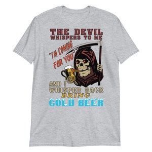 May include: A grey t-shirt featuring a graphic of a skeleton in a hooded robe holding a beer and a cigar. The text on the shirt reads "The Devil whispers to me "I'm coming for you" and I whisper back bring cold beer".