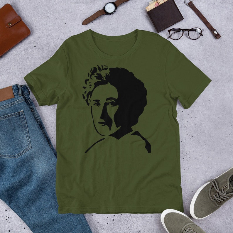 May include: A green t-shirt with a black silhouette of a woman's face on the front.