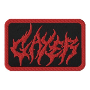 Peut inclure: Patch brodé rouge avec le mot "Slayer" dans une police stylisée sur un fond noir avec une bordure rouge.