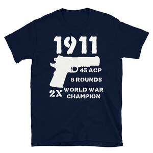 May include: Navy blue t-shirt with a white silhouette of a 1911 pistol, the text "1911", "45 ACP", "8 Rounds", "2X World War Champion" printed on the front.