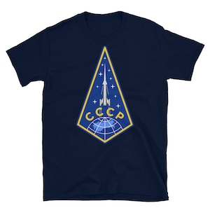 May include: A navy blue t-shirt with a yellow and blue emblem featuring a rocket and the text "CCCP".