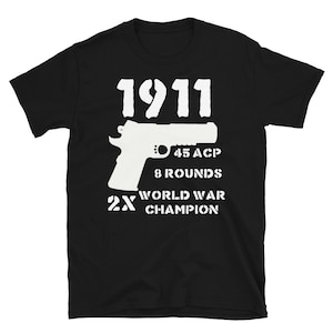 May include: Black t-shirt with white text and a silhouette of a pistol. The text reads "1911", "45 ACP", "8 Rounds", "2X World War Champion".