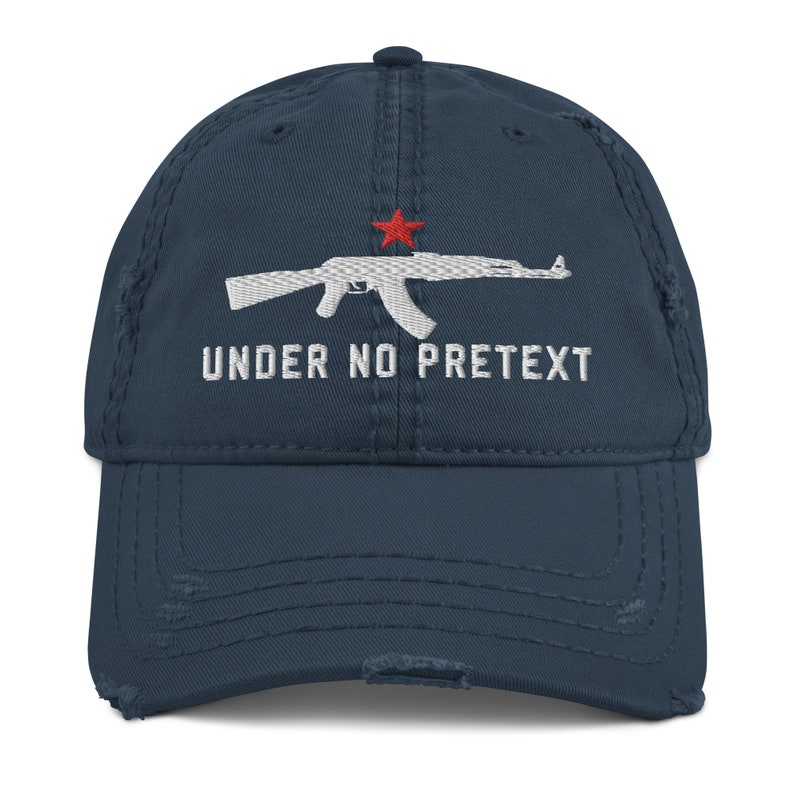 May include: A distressed blue baseball cap with a white embroidered image of an AK-47 rifle and the text "UNDER NO PRETEXT".