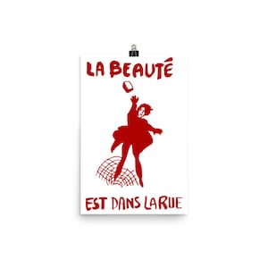 May include: A red poster with the text "LA BEAUT&Eacute; EST DANS LA RUE" and a silhouette of a person throwing a brick.