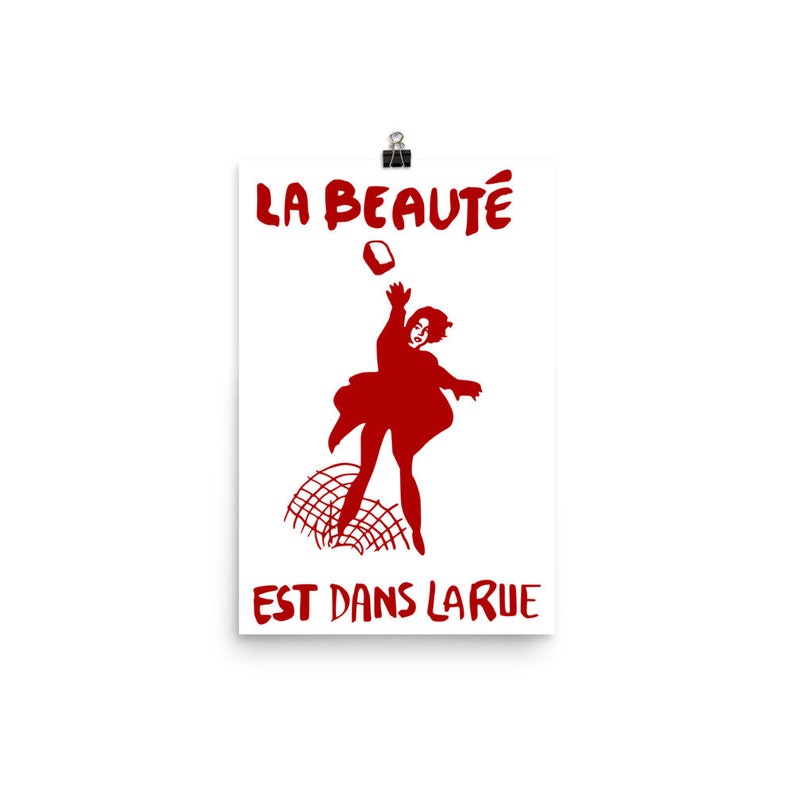 May include: A red poster with the text "LA BEAUT&Eacute; EST DANS LA RUE" and a silhouette of a person throwing a brick.