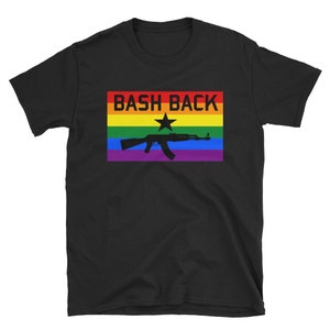 Könnte beinhalten: Schwarzes T-Shirt mit einer Regenbogenflagge und dem Text "Bash Back" in schwarzen Buchstaben. Eine schwarze Silhouette eines Gewehrs mit einem Stern befindet sich auf der Flagge.