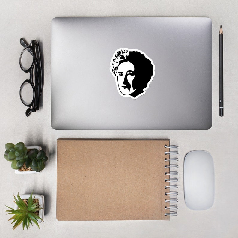 May include: A black and white silhouette sticker of a woman with short, curly hair. The sticker is on a silver laptop computer.