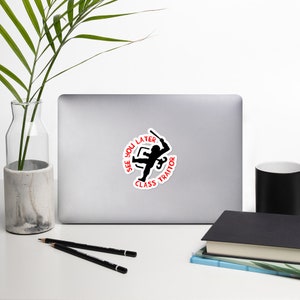 May include: A white laptop with a black and red sticker that says "See you later, class traitor" with a silhouette of a person holding a weapon.
