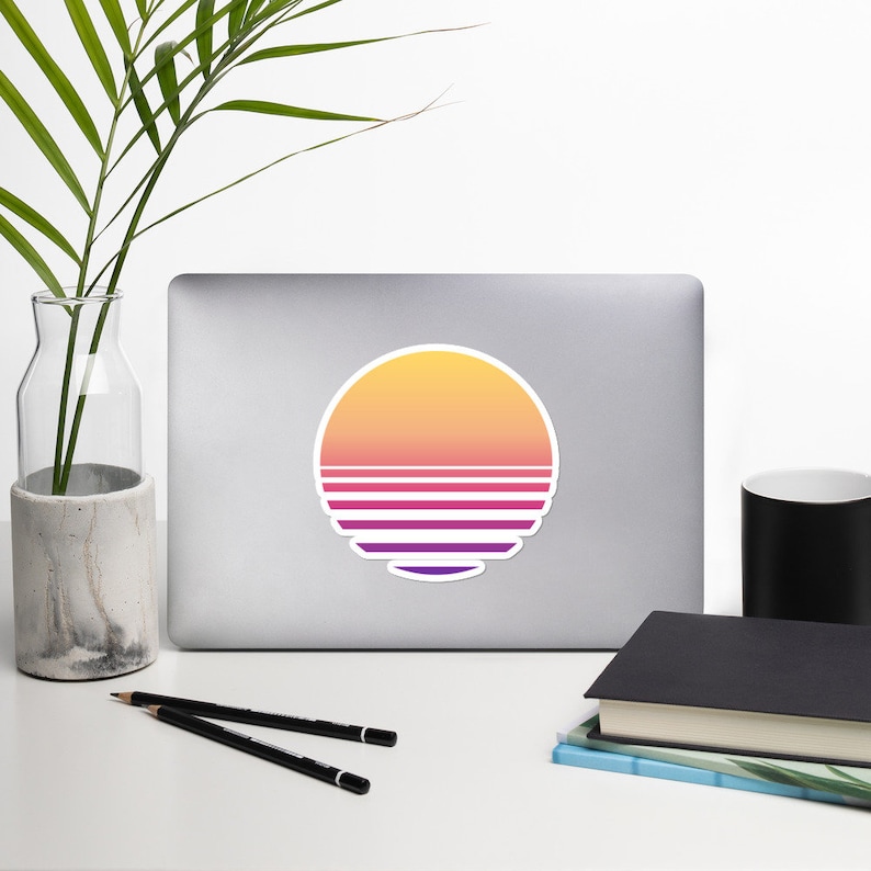 May include: A sticker with a retro sunset design. The sun is a circle with a gradient of yellow, orange, pink, and purple. The sun has horizontal stripes in a gradient of purple, pink, and white.