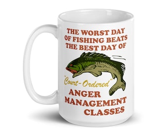 May include: White ceramic coffee mug with a green and brown illustration of a fish jumping out of the water. The text on the mug reads "The worst day of fishing beats the best day of "Court-Ordered" Anger Management Classes."