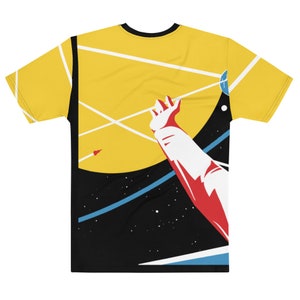 May include: A yellow t-shirt featuring a retro space-themed graphic. The design includes a large yellow sun, a red arm reaching out, and a black background with stars and a blue line. The shirt has a black collar.