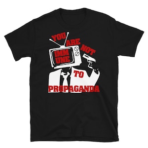 May include: Black t-shirt with a white graphic of a person holding a television with the text "You are not immune to propaganda".