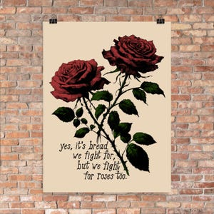 Puede incluir: Un fondo beige con una ilustración en blanco y negro de dos rosas rojas con hojas y espinas verdes. El texto "yes, it's bread we fight for, but we fight for roses too." está escrito en cursiva negra.