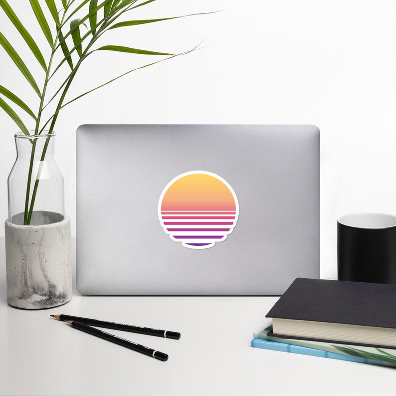 May include: A round sticker with a retro sunset design. The sticker features a yellow, orange, and pink gradient with horizontal stripes in purple and white.