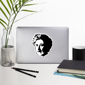 May include: Black and white silhouette sticker of a woman with short hair. The sticker is on a silver laptop.