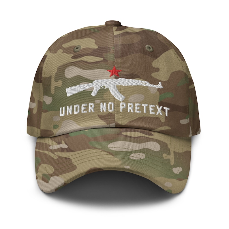 May include: A camouflage baseball cap with a white embroidered AK-47 rifle and the text "UNDER NO PRETEXT" in white. A red star is embroidered above the rifle.