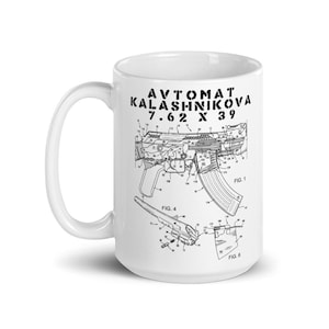 Pode incluir: Caneca de cerâmica branca com um diagrama esquemático preto de um rifle de assalto AK-47, com o texto "AVTOMAT KALASHNIKOVA 7.62 X 39". A caneca tem uma alça curva e é adequada para bebidas quentes.