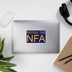 May include: A blue and yellow sticker with the text "Repeal the NFA" on a laptop.