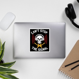 May include: Black and white sticker featuring a skull wearing headphones and crossed lightning bolts. The text reads "Can't Stop The Signal".