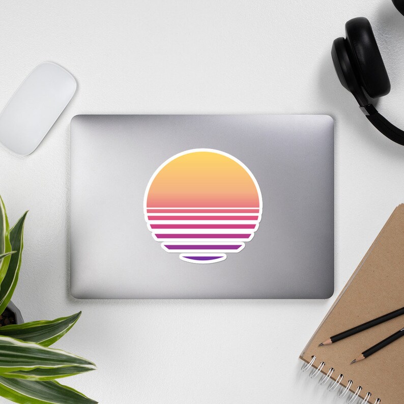 May include: A round sticker with a retro sunset design. The sun is yellow and orange, with a purple and pink horizon line.