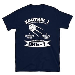 May include: A navy blue t-shirt with a white graphic of Sputnik 1, the first artificial satellite launched into space. The graphic includes the text "SPUTNIK 1", "Простейший Спутник-1", "4 ОКТЯБРЬ 1957", "4 ЯНВАРЬ 1958", and "РАЗРАБОТАН ОКБ-1".