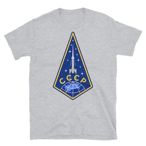 May include: A gray t-shirt with a blue and yellow patch featuring a rocket launching from a globe with the text "CCCP" in yellow.