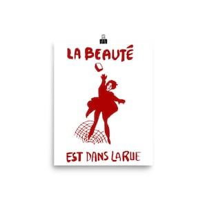 May include: A red silhouette of a person throwing a brick with the text "LA BEAUT&Eacute; EST DANS LA RUE" in red.