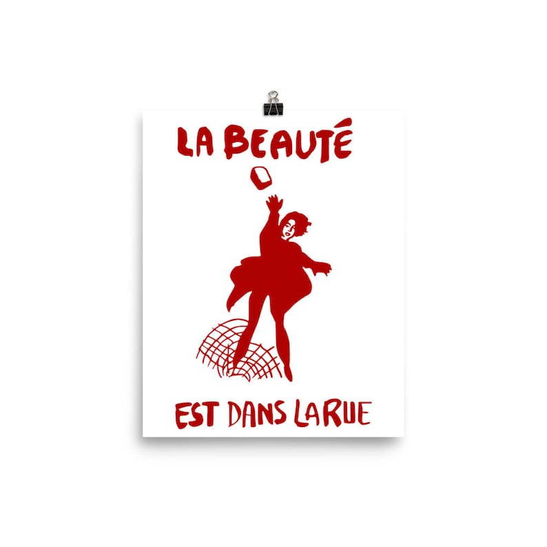 May include: A red silhouette of a person throwing a brick with the text "LA BEAUT&Eacute; EST DANS LA RUE" in red.