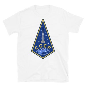 May include: White t-shirt with a blue and gold emblem featuring a rocket launching from a globe with the text "CCCP" in gold letters.