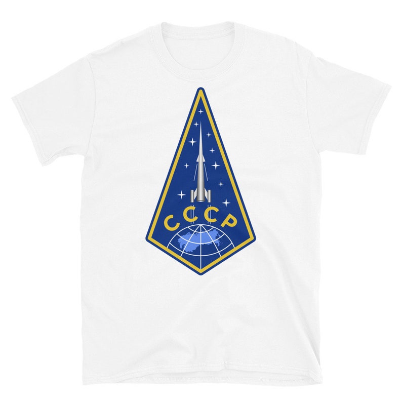 May include: White t-shirt with a blue and gold emblem featuring a rocket launching from a globe with the text "CCCP" in gold letters.