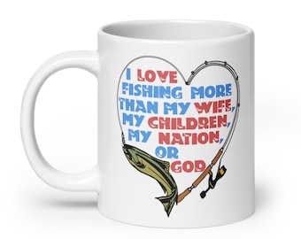 Pode incluir: Caneca de café de cerâmica branca com um design de coração vermelho e azul. O coração apresenta uma vara de pesca e um peixe. O texto na caneca diz "Eu amo pescar mais do que minha esposa, meus filhos, minha nação ou Deus."
