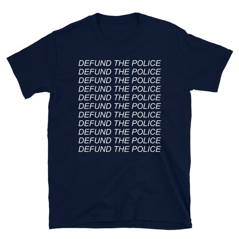 Peut inclure: T-shirt bleu marine avec la phrase "DEFUND THE POLICE" r&eacute;p&eacute;t&eacute;e 11 fois en texte blanc.