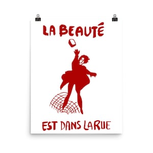 May include: Red silhouette of a person throwing a brick with the text "LA BEAUT&Eacute; EST DANS LA RUE" in red.