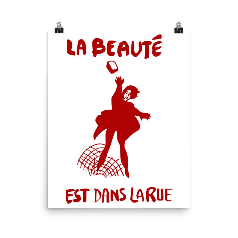 May include: Red silhouette of a person throwing a brick with the text "LA BEAUT&Eacute; EST DANS LA RUE" in red.