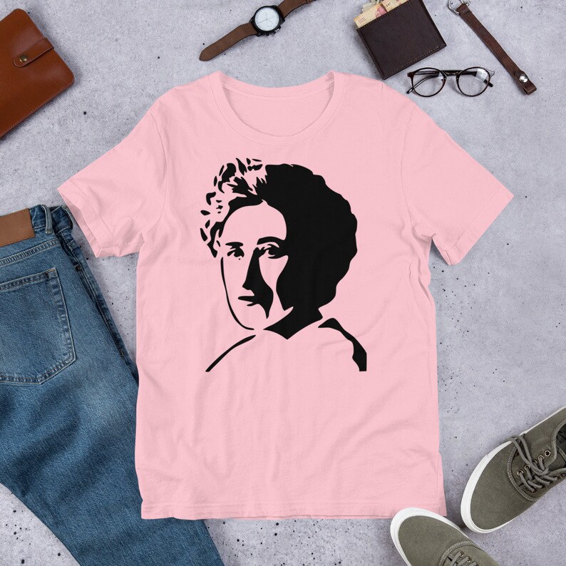 May include: Pink t-shirt with a black and white silhouette of a woman's face.