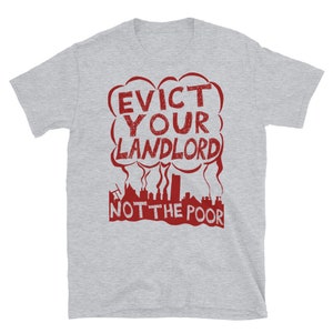 Op de afbeelding: Grijs T-shirt met rode tekst die "Evict Your Landlord Not The Poor" luidt, met een afbeelding van een skyline met rook uit de gebouwen.