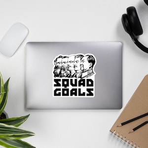 Könnte beinhalten: Schwarzweiß-Illustration von fünf Männergesichtern mit dem Text "Squad Goals" darunter. Die Männer tragen alle Anzüge und haben einen ernsten Gesichtsausdruck.