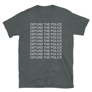 Peut inclure: Un t-shirt gris fonc&eacute; chin&eacute; avec la phrase "DEFUND THE POLICE" r&eacute;p&eacute;t&eacute;e 11 fois en texte blanc.