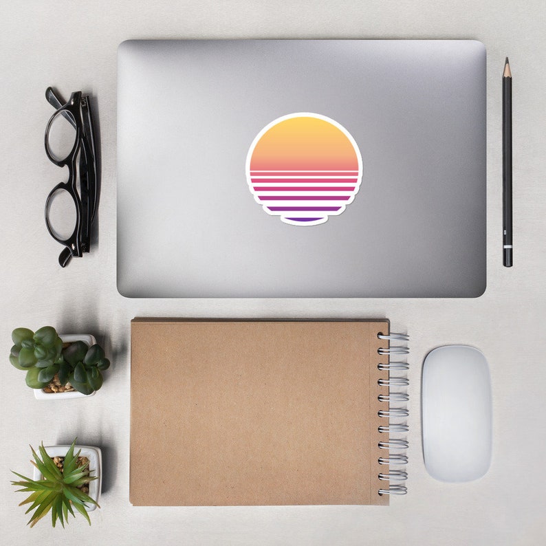 May include: A laptop computer with a sticker of a sunset with pink, orange, and purple stripes on a white background.