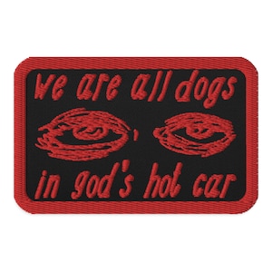 May include: Red embroidered patch with a black background. The patch reads "We are all dogs in god's hot car" with two red eyes above the text.