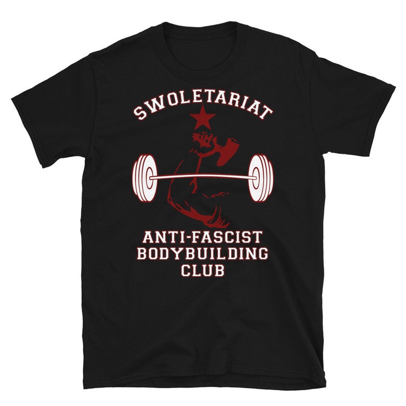 May include: Black t-shirt with red and white text that reads "Swole-tariat Anti-Fascist Bodybuilding Club". A red silhouette of a bicep lifting a barbell is in the centre of the shirt.