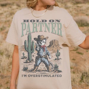 Comfort Colors® Hold On Partner I&#39;m Overstimulated Cowboy Cat Shirt, Funny Animal Meme T-Shirt, Introvert Humor, Trendy Western Graphic Tee