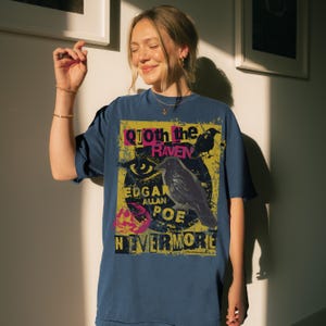 May include: Navy blue t-shirt with a graphic design inspired by Edgar Allan Poe's poem "The Raven." The design includes a raven illustration, the text "Quoth the Raven," and the word "Nevermore."