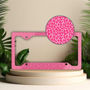 May include: Pink license plate frame with a leopard print design.